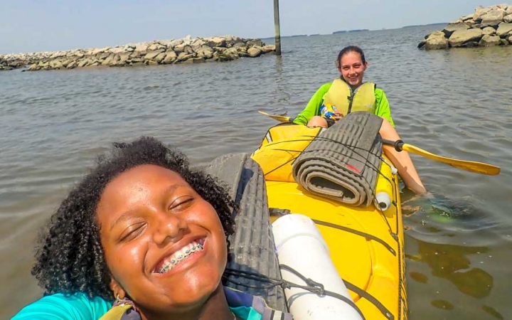 two girls in a kayak smile on an outward bound course